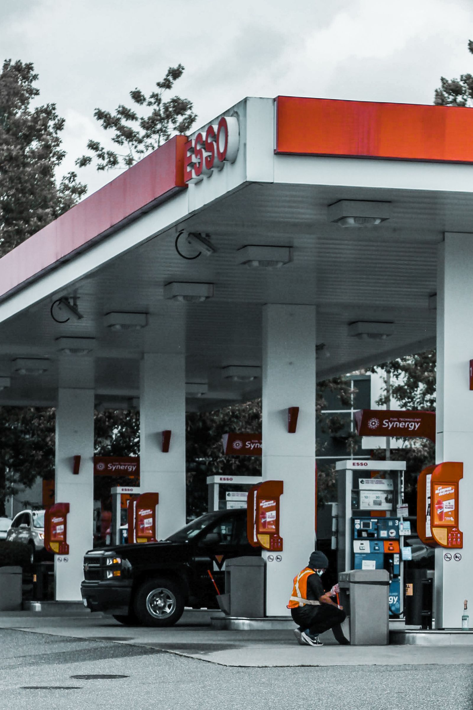 Gas station forecourt with a car refueling under a bright canopy