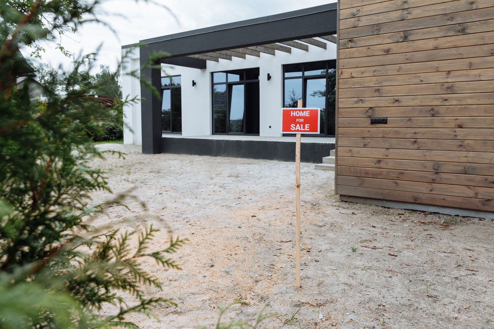 Modern house exterior with a home for sale sign in the front yard